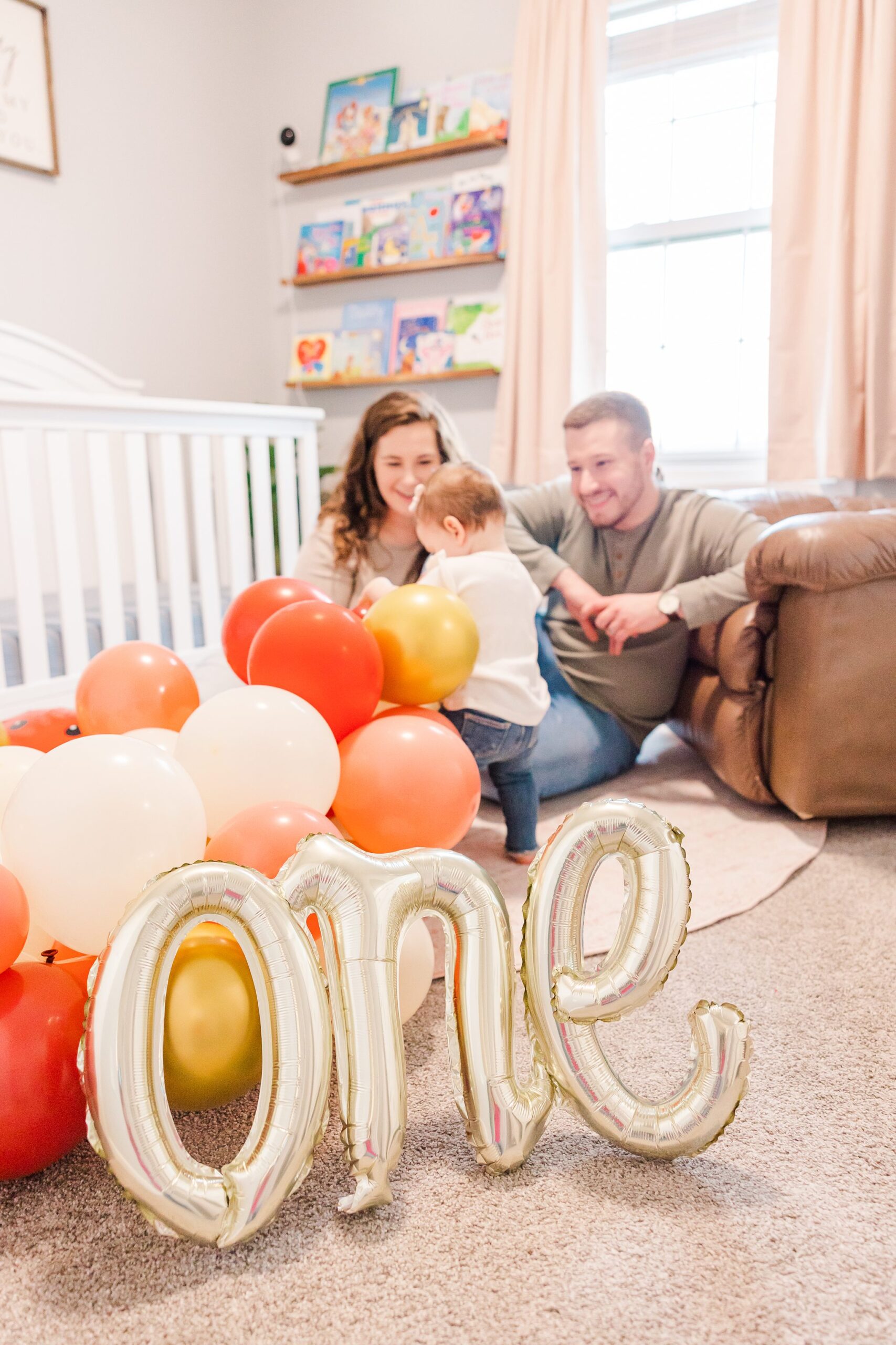 one year old with balloons on floor and parents looking on
