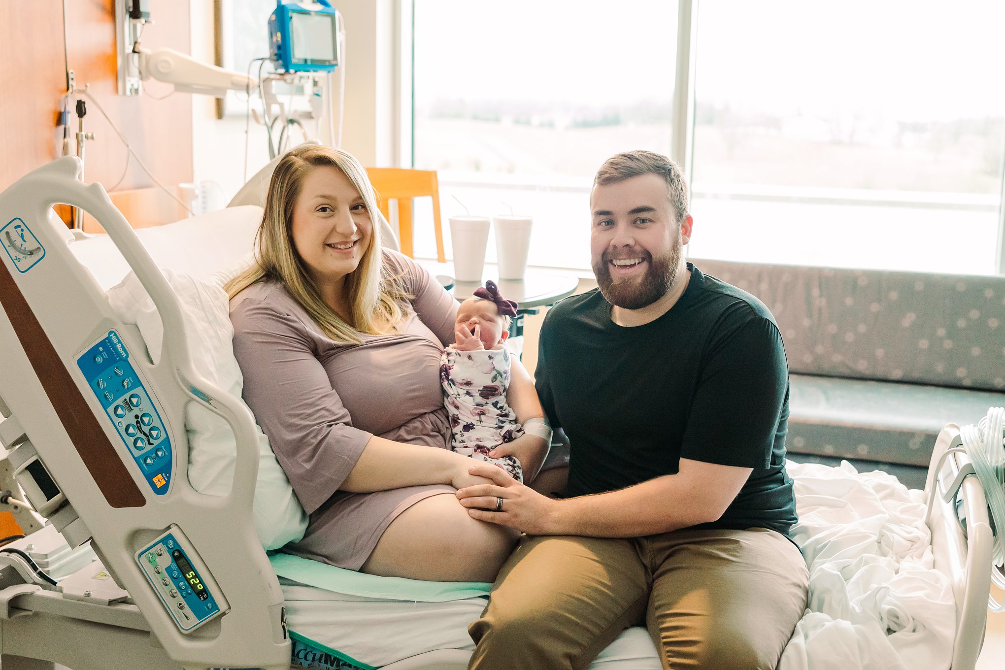 parents holding baby girl on hospital bed