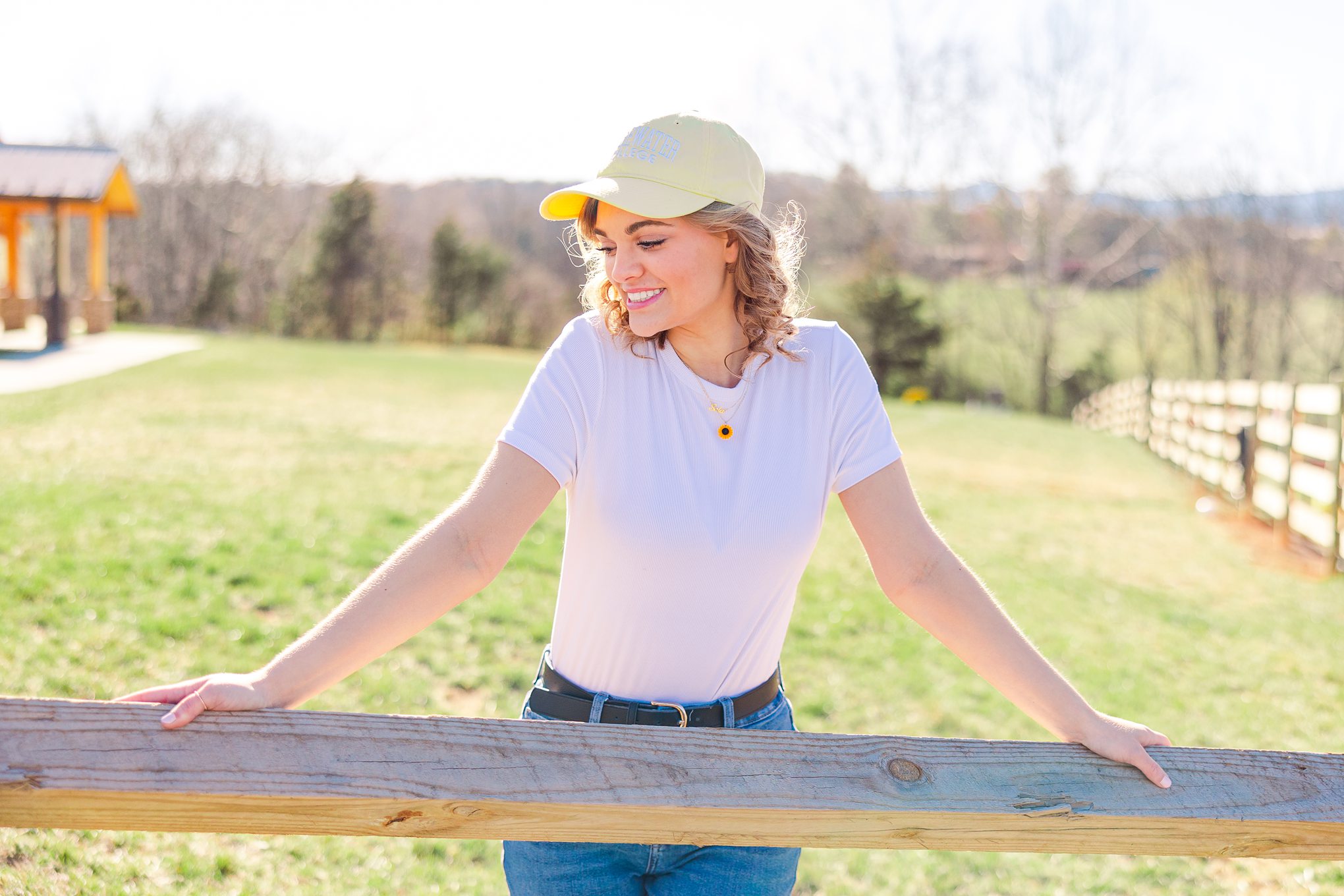 young girl leaning on fence with yellow hat on