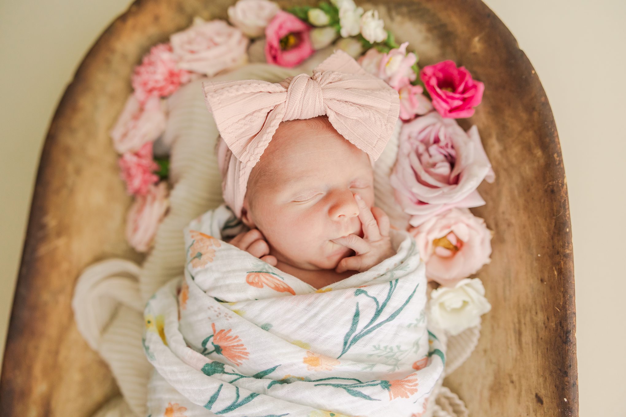 newborn girl surrounded by flowers in a bread bowl 