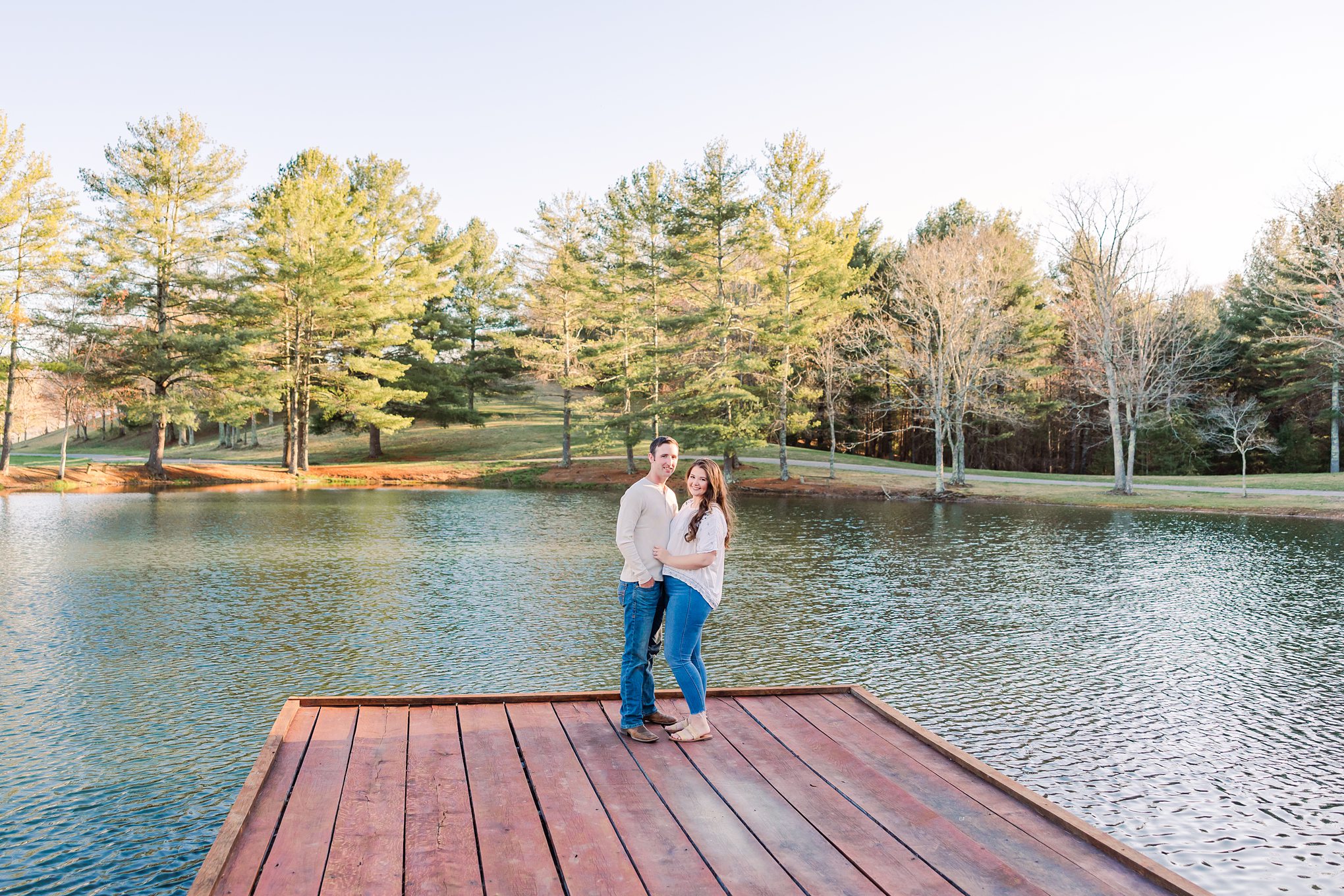 engaged couple on a dock surrounded by pine trees