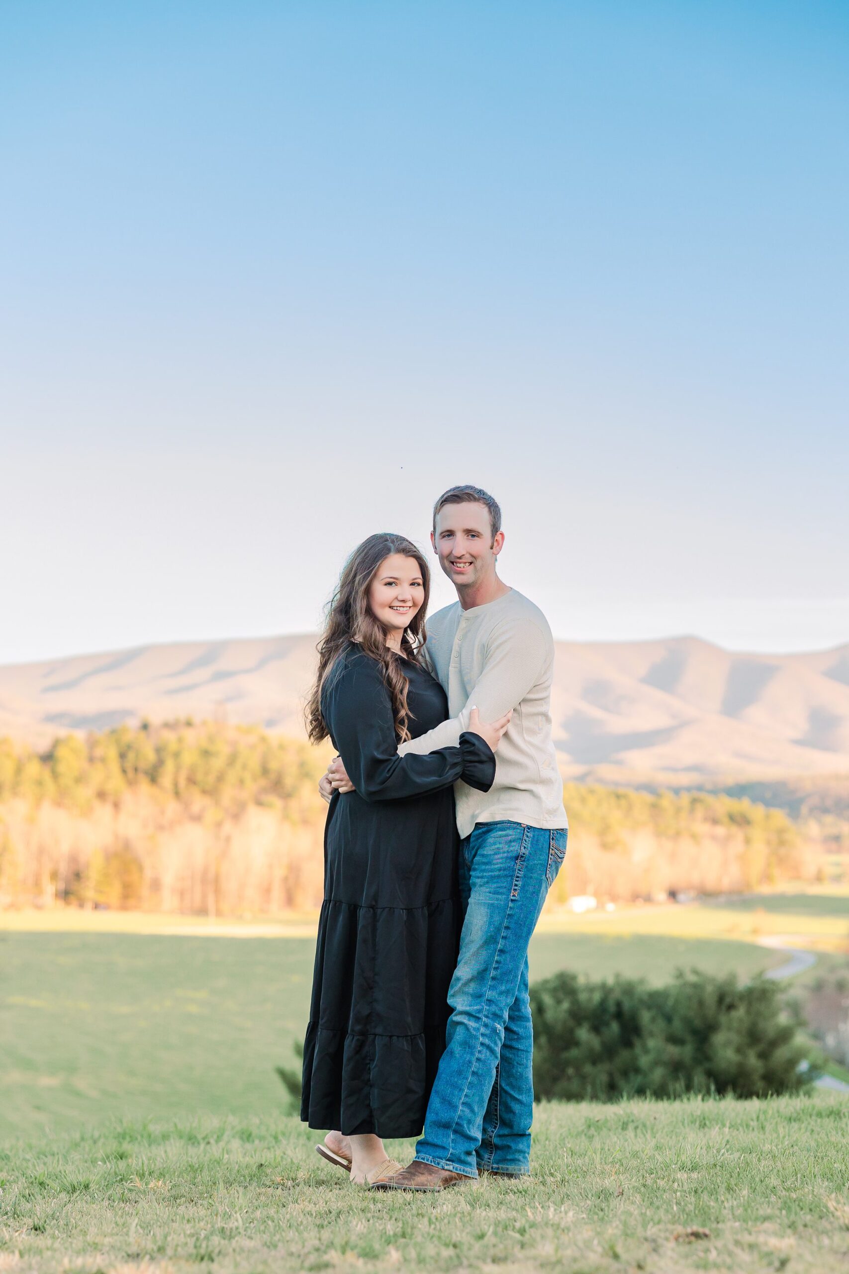 engaged couple smiling at camera with mountains in background