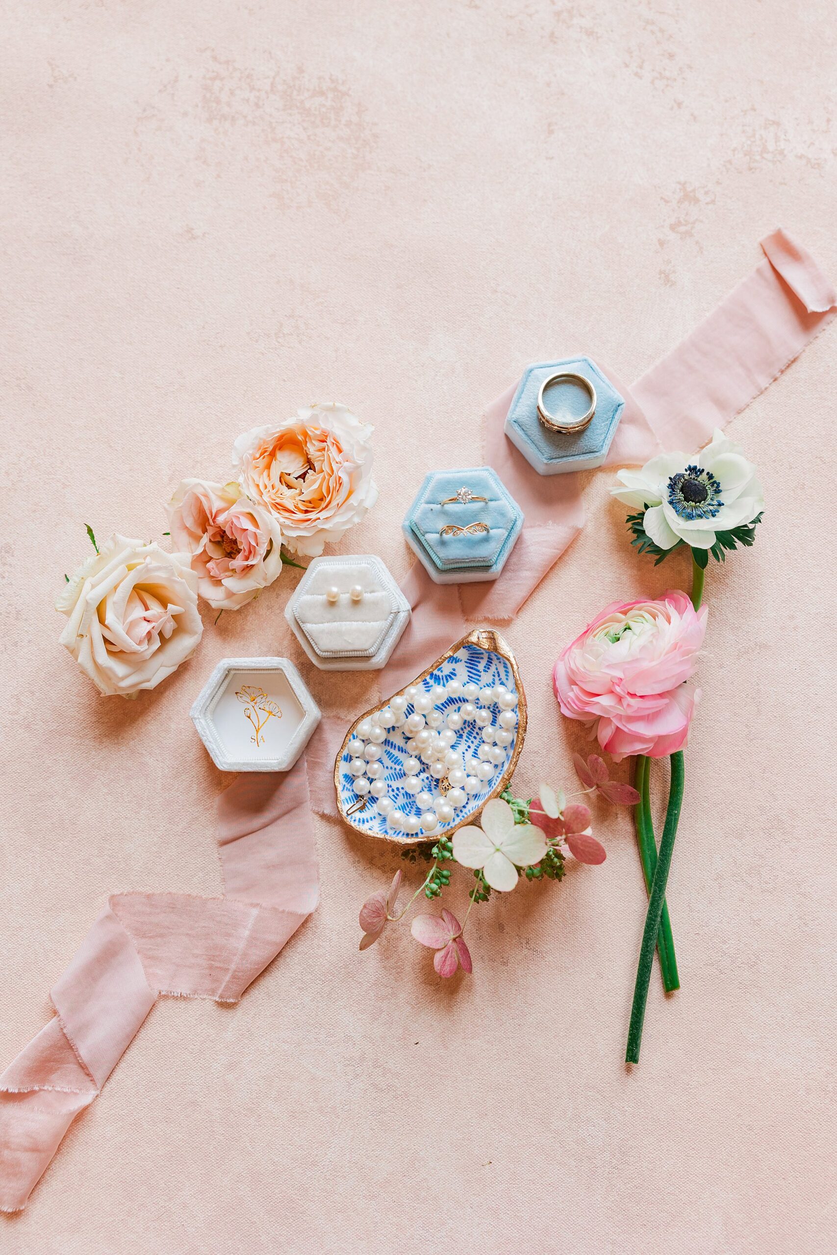 Bridal details shot that involves ribbons, florals, ring boxes, and oyster dish