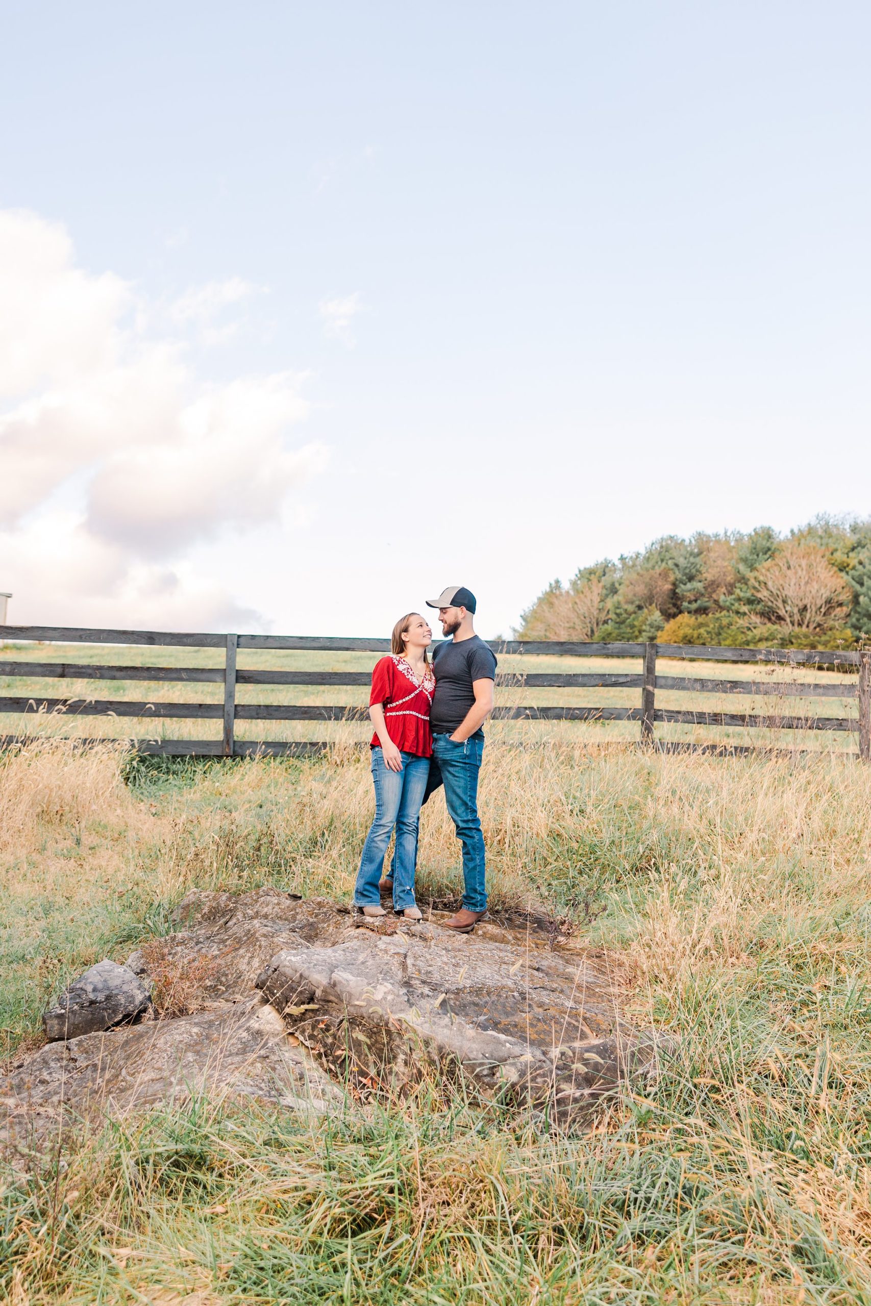 engaged couple on rock in field