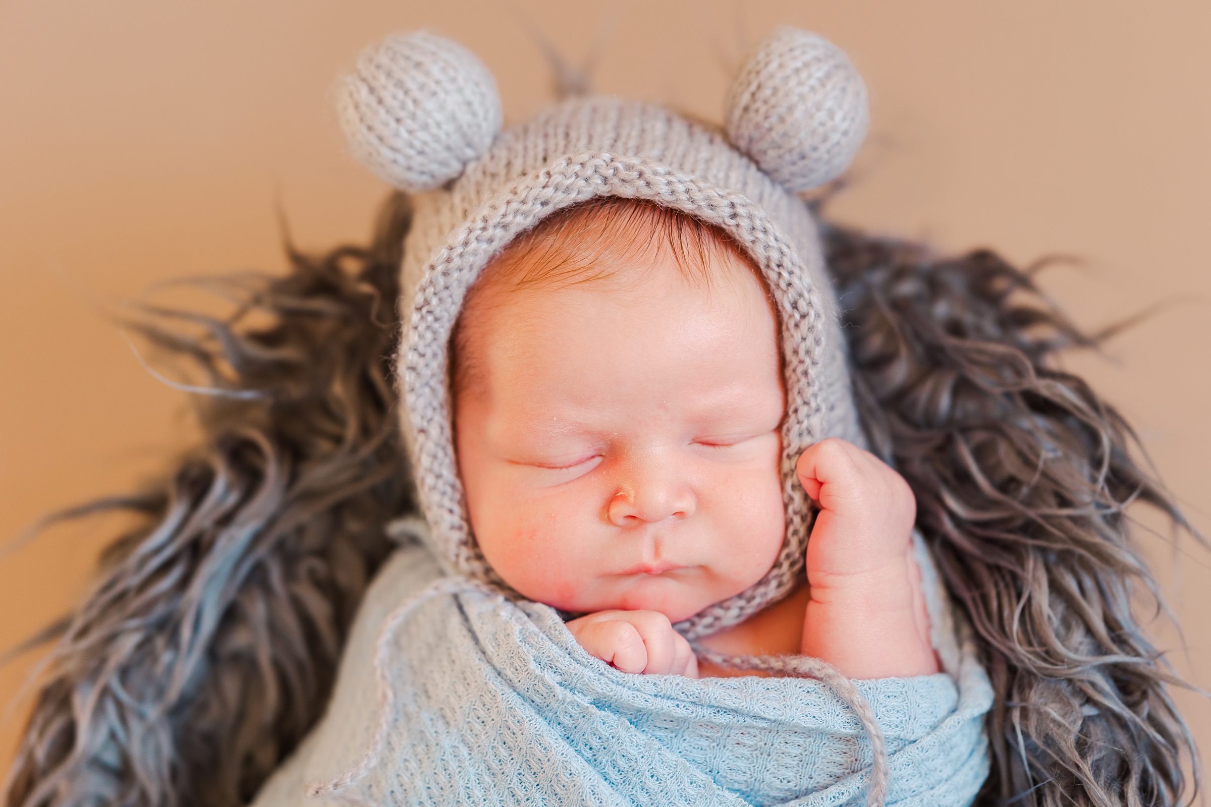 newborn boy wearing ball pom hat
